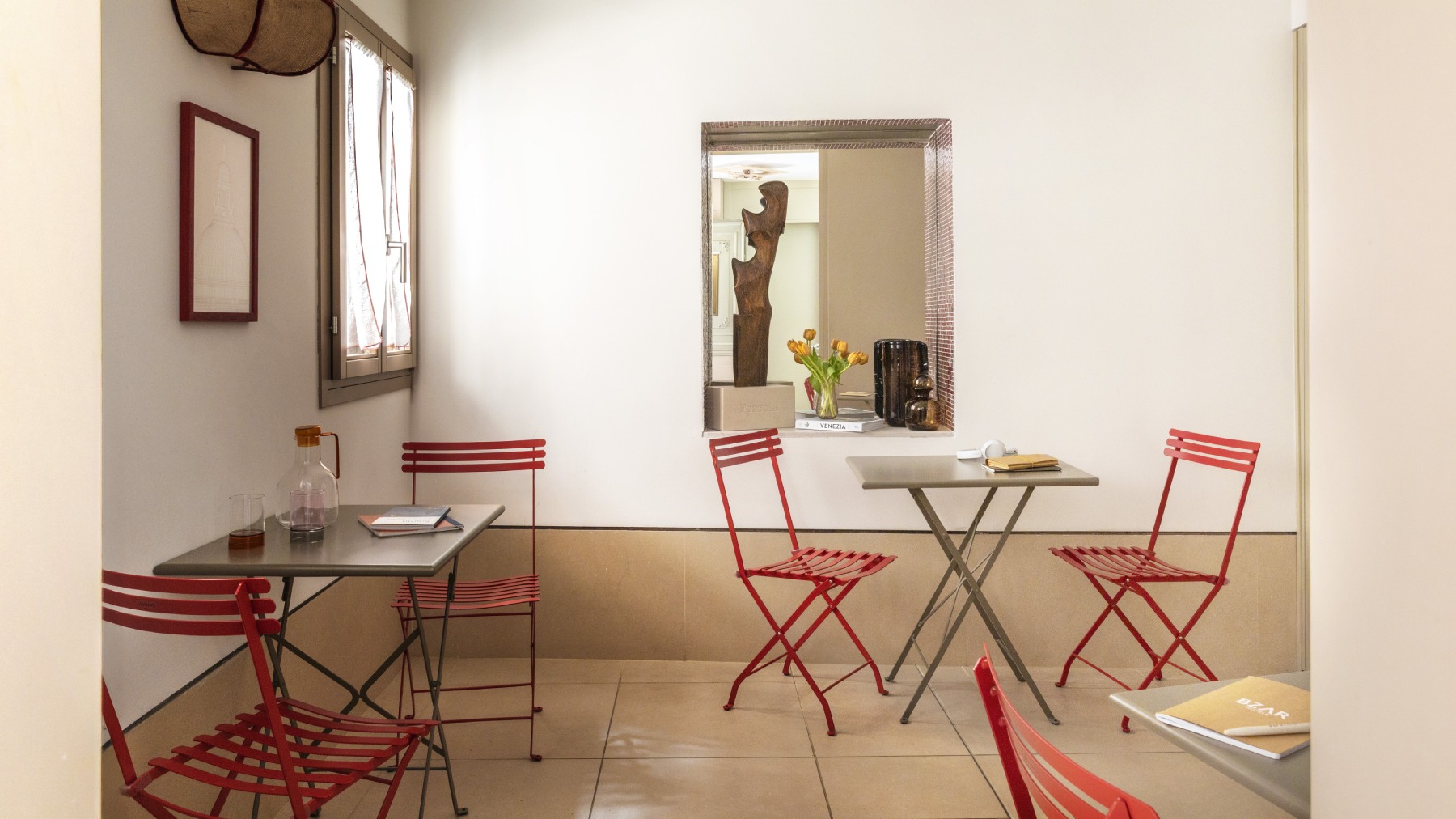 Area comune di design a Venezia con tavolini bistro, sedie rosse e atmosfera accogliente - Ca' La Stampa, BZAR hotels a Venezia